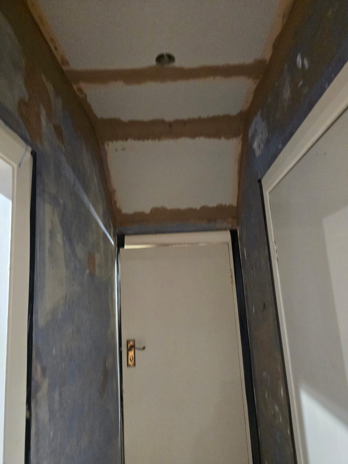 Hallway mid-refurbishment with fresh plasterwork